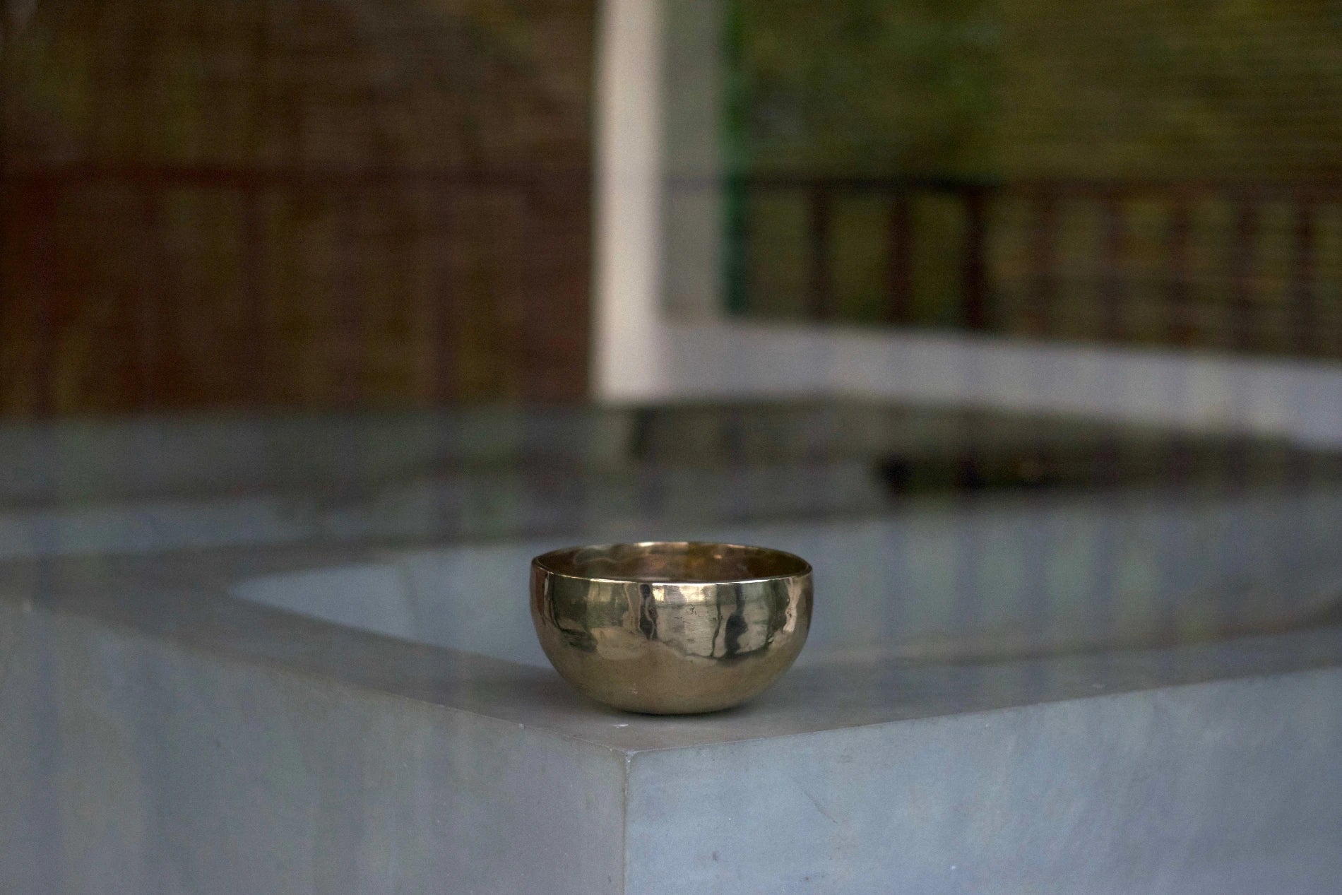 Sonner Sound - Eine Klangschale steht auf dem Rand einer puristischen Betonbadewanne