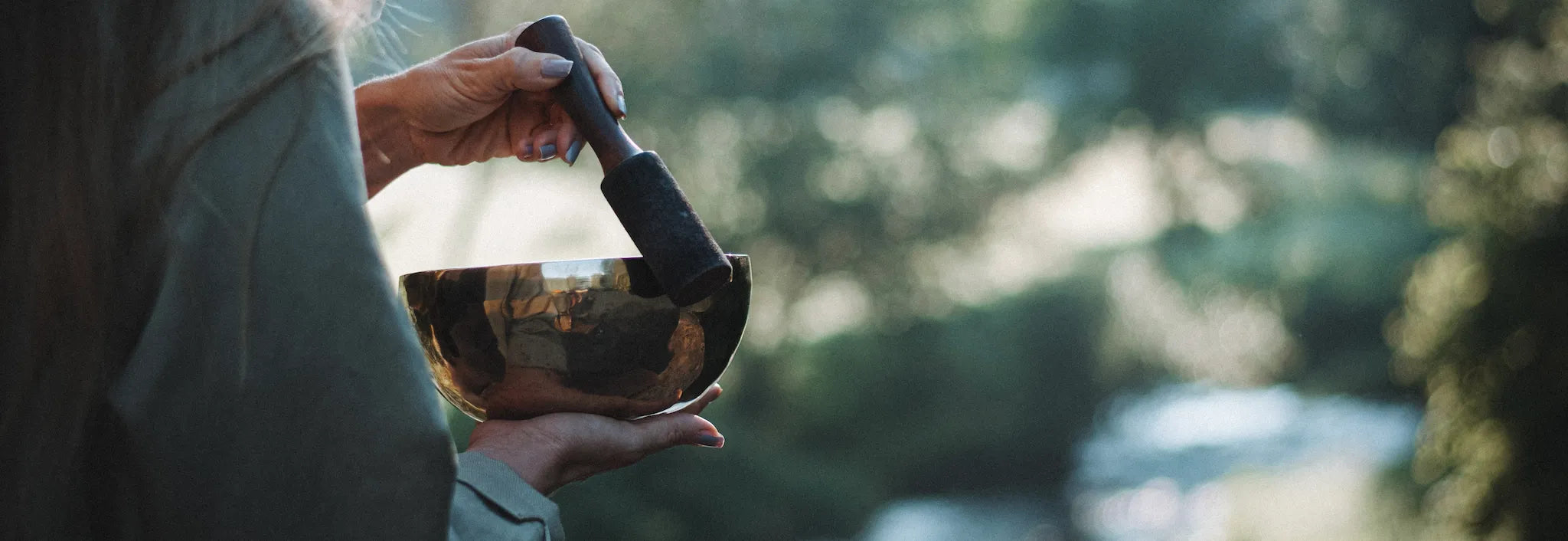 Sonner Sound Gründerin Raphaela spielt eine Klangschale in der Natur